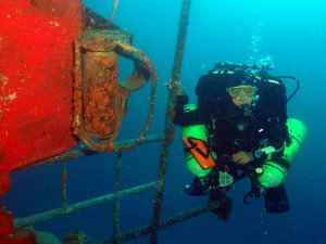Diver on wreck handrail